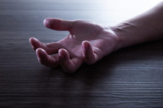 Human Hand of a man unconscious on the floor.