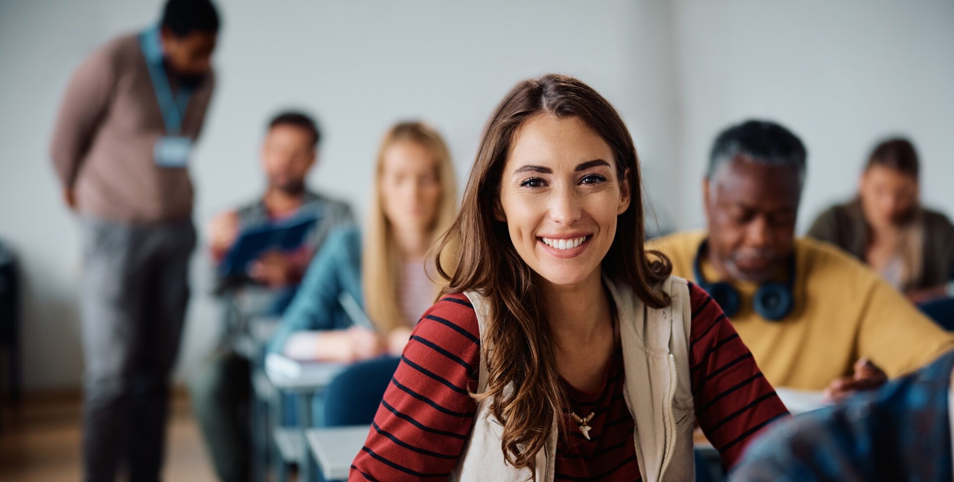 Happy female student learning in the classroom and looking at camera.